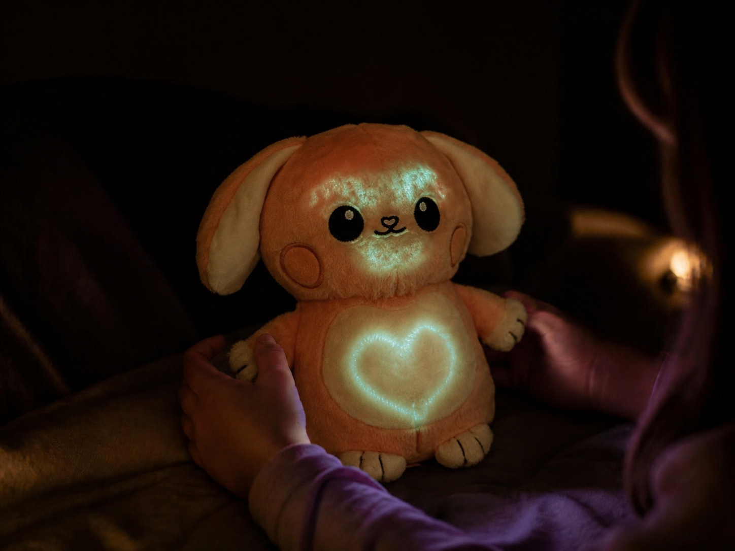 A child holding Glow Buddy in the dark with a glowing green heart drawn on it.